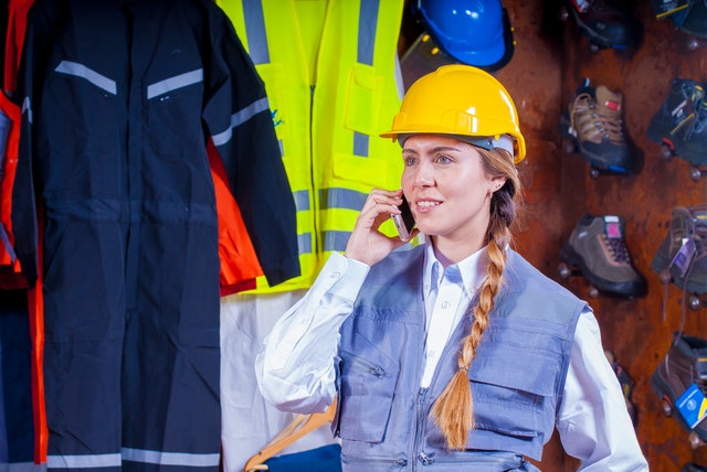Mladá žena-stavební dělnice s mobilem u ucha
